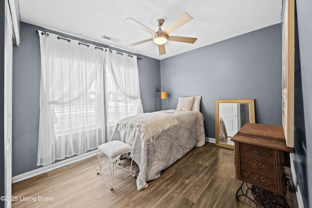 bedroom with visible vents, baseboards, wood finished floors, and a ceiling fan