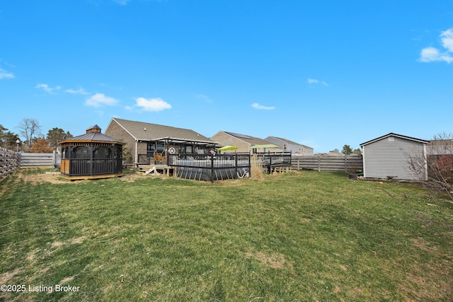 view of yard featuring a gazebo, a fenced backyard, and an outdoor structure