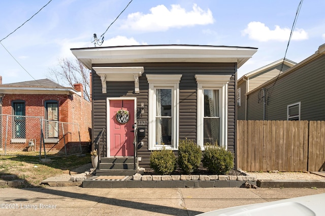 shotgun-style home featuring entry steps and fence