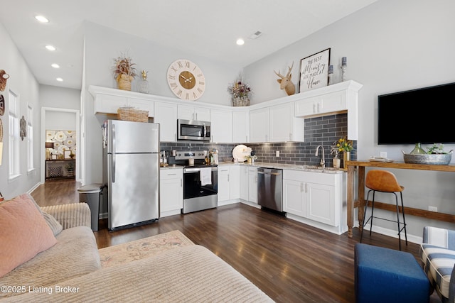 kitchen with dark wood-style floors, white cabinetry, stainless steel appliances, and a sink