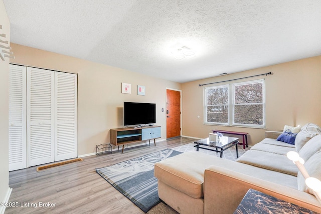 living area featuring wood finished floors, baseboards, and a textured ceiling