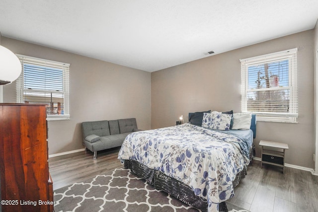 bedroom featuring visible vents, baseboards, and wood finished floors