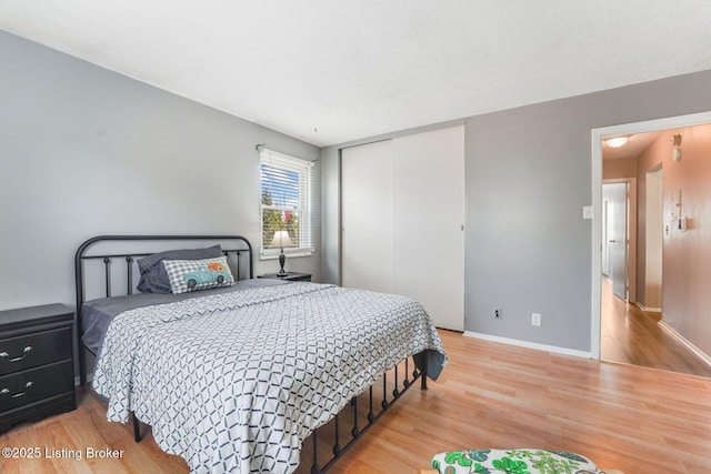 bedroom featuring a closet, baseboards, and wood finished floors