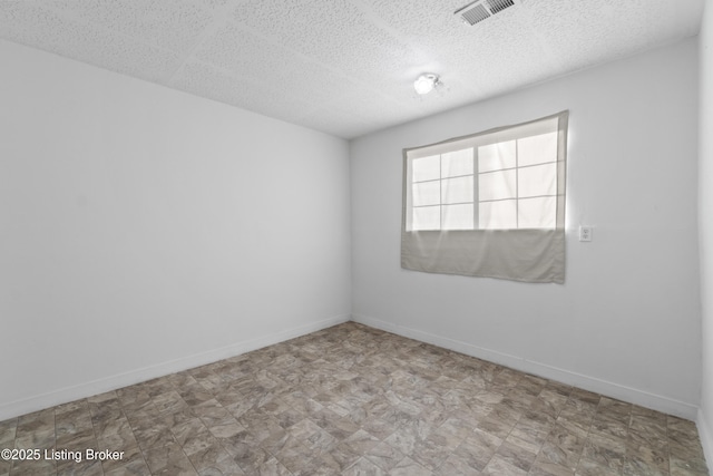 spare room featuring tile patterned floors, baseboards, visible vents, and a textured ceiling