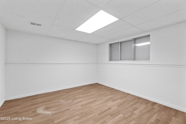 unfurnished room featuring light wood-style flooring, baseboards, visible vents, and a drop ceiling