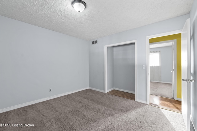 unfurnished bedroom featuring carpet, visible vents, a closet, and a textured ceiling