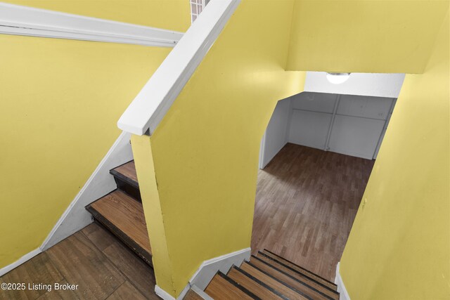 staircase featuring wood finished floors and baseboards