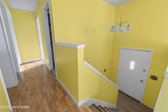 foyer entrance with baseboards, an inviting chandelier, and wood finished floors