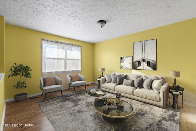 living room with baseboards, wood finished floors, visible vents, and a textured ceiling