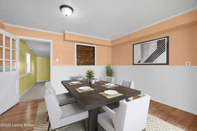 dining space featuring a textured ceiling, crown molding, baseboards, and wood finished floors