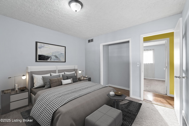 bedroom with visible vents, a textured ceiling, and baseboards