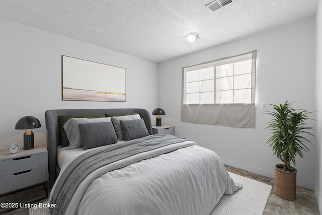 bedroom with visible vents, baseboards, and a textured ceiling