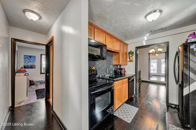 kitchen featuring visible vents, black appliances, tasteful backsplash, dark countertops, and dark wood finished floors