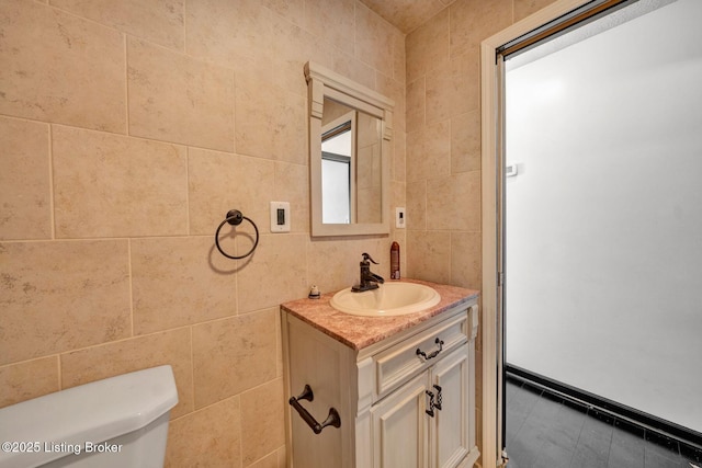 half bath with toilet, tile walls, and vanity