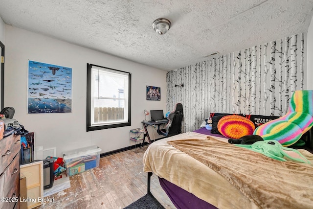 bedroom featuring visible vents, baseboards, a textured ceiling, and hardwood / wood-style flooring