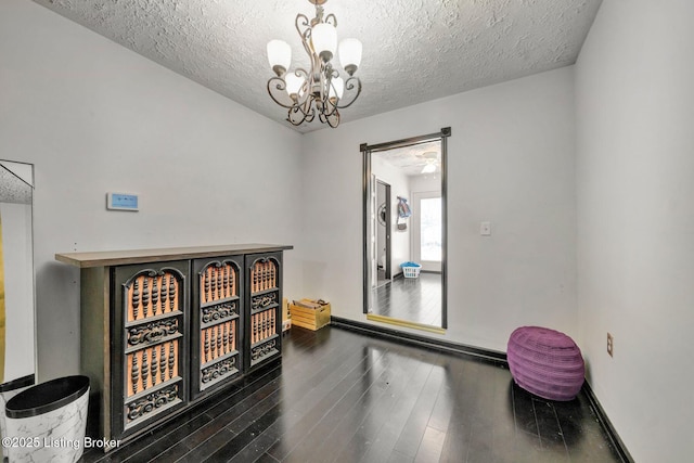 interior space featuring baseboards, dark wood-type flooring, a chandelier, and a textured ceiling