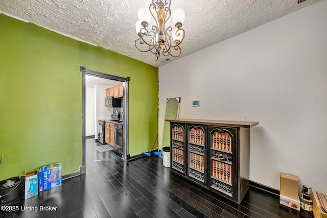 interior space with a textured ceiling, dark wood-style floors, baseboards, and a chandelier