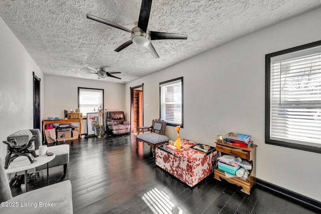 living room with a textured ceiling, baseboards, and wood finished floors