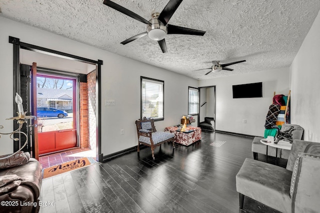 living area with a healthy amount of sunlight, a textured ceiling, baseboards, and wood finished floors