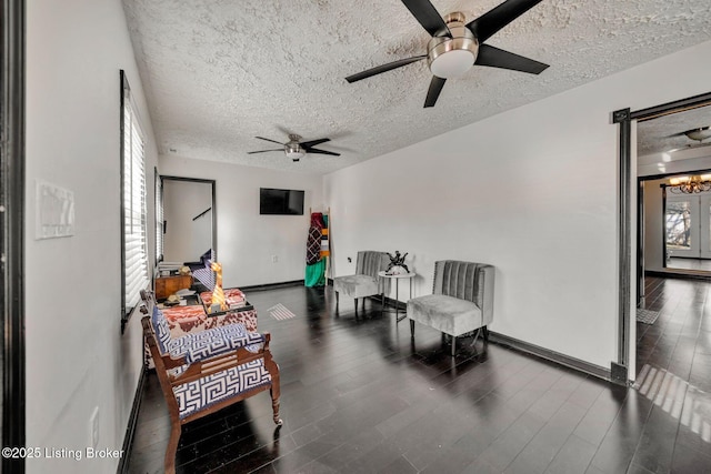 sitting room with baseboards, a textured ceiling, and wood finished floors