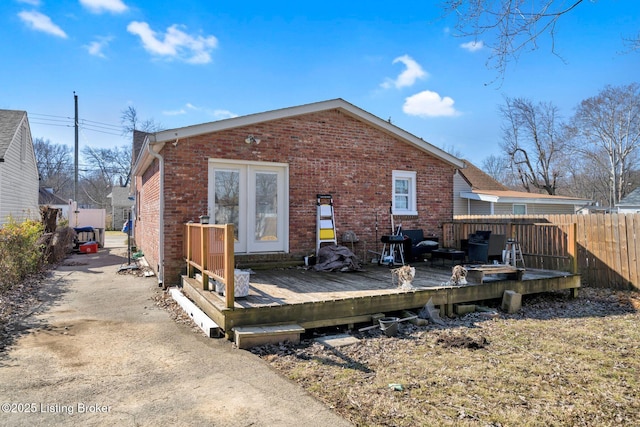 rear view of property with brick siding, a deck, and fence