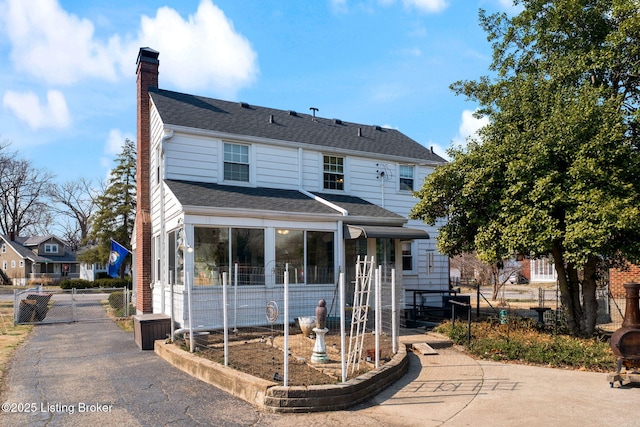 view of front of home featuring fence, roof with shingles, a chimney, and a gate