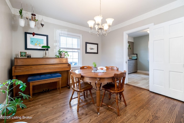 dining area featuring crown molding, a notable chandelier, wood finished floors, and baseboards