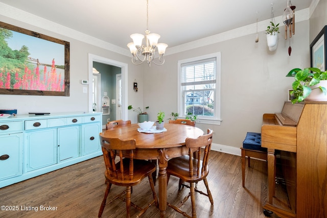 dining room with a notable chandelier, wood finished floors, baseboards, and ornamental molding