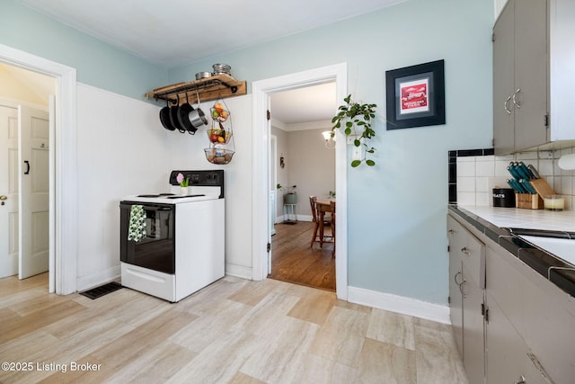 kitchen with visible vents, light wood-style flooring, white electric range, light countertops, and decorative backsplash