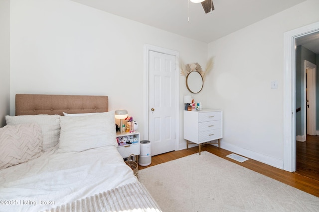 bedroom with visible vents, baseboards, wood finished floors, and a ceiling fan