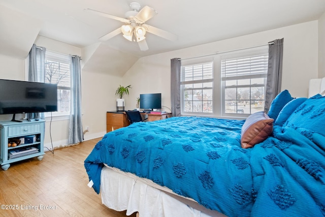 bedroom with ceiling fan, baseboards, wood finished floors, and vaulted ceiling