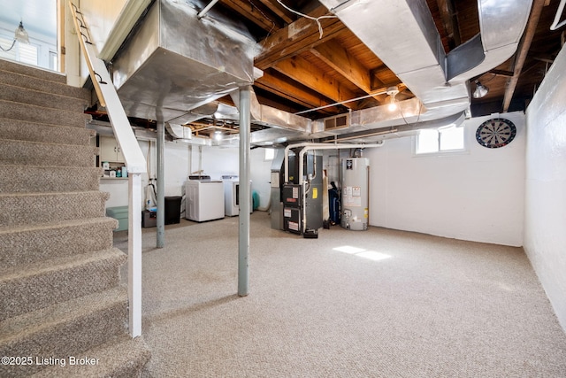 below grade area with heating unit, visible vents, separate washer and dryer, stairs, and gas water heater