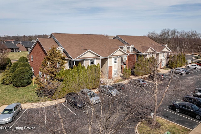 exterior space featuring brick siding, a residential view, and uncovered parking