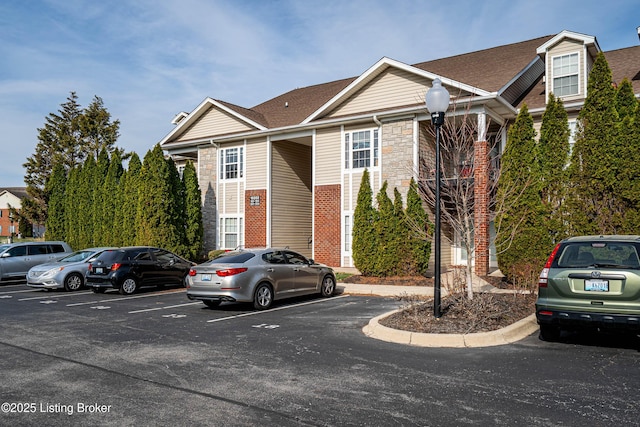 view of front facade featuring stone siding and uncovered parking