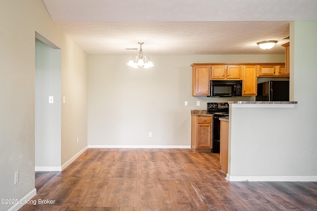 kitchen featuring black appliances, wood finished floors, baseboards, and a chandelier