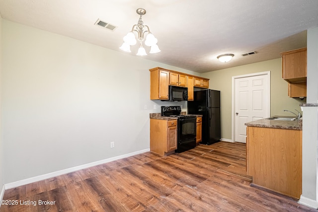 kitchen featuring a notable chandelier, visible vents, black appliances, and a sink