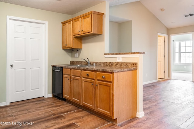 kitchen with visible vents, dark wood-type flooring, a sink, dishwasher, and vaulted ceiling