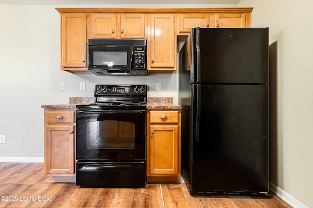 kitchen with black appliances, brown cabinetry, baseboards, and light wood finished floors