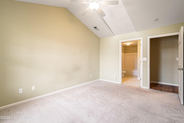 unfurnished bedroom featuring visible vents, ensuite bath, carpet, baseboards, and vaulted ceiling