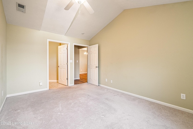 unfurnished bedroom with visible vents, light colored carpet, baseboards, and vaulted ceiling