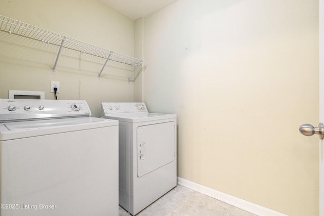 clothes washing area with laundry area, washing machine and dryer, and baseboards