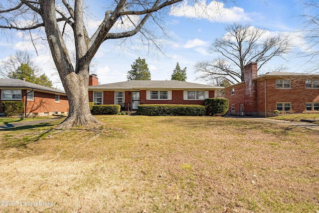 view of front of house with brick siding, a front yard, and a chimney