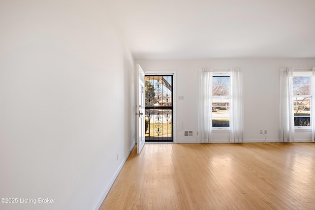 empty room with visible vents, light wood-style flooring, and baseboards