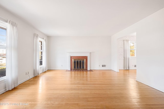 unfurnished living room with a fireplace, light wood-type flooring, and a wealth of natural light