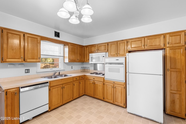 kitchen with white appliances, light countertops, a chandelier, and a sink