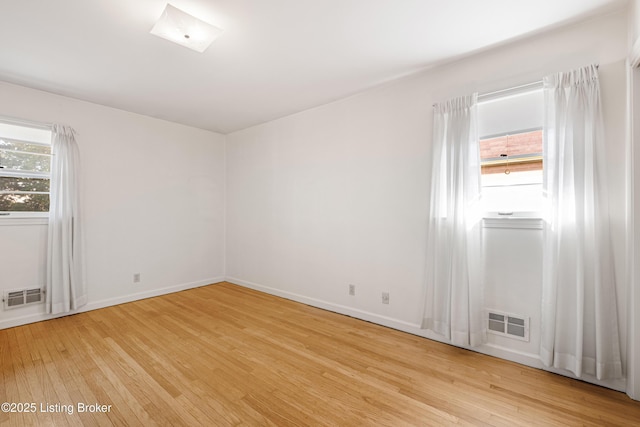 empty room featuring baseboards, visible vents, and light wood-type flooring