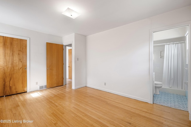 unfurnished bedroom with visible vents, light wood-style flooring, ensuite bathroom, and baseboards