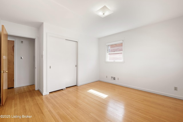 unfurnished bedroom featuring visible vents, baseboards, a closet, and light wood finished floors