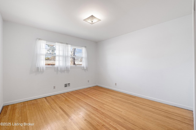 spare room with visible vents, light wood-style floors, and baseboards