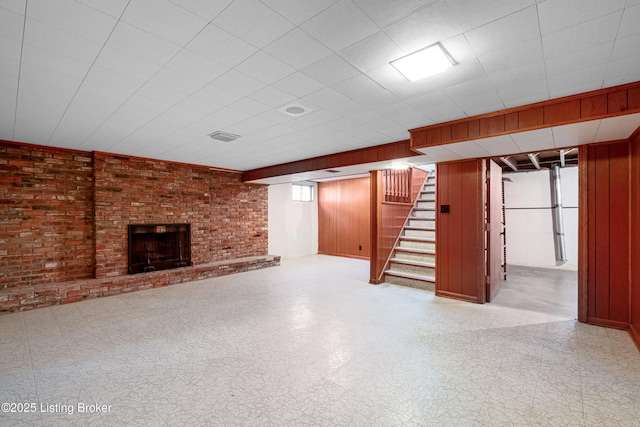 basement with tile patterned floors, stairway, wood walls, and brick wall